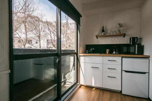 a kitchen with white cabinets and a large window at Hotel Villa Hakuba by HHG in Hakuba