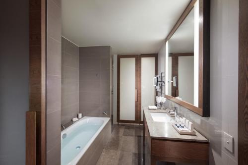 a bathroom with a tub and two sinks and a mirror at Pan Pacific Melbourne in Melbourne