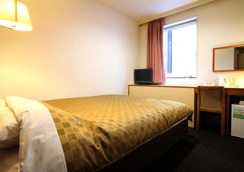 a hotel room with a bed and a desk and a window at Hotel Trend Funabashi in Funabashi