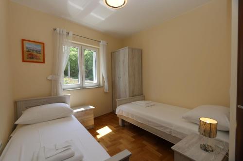 2 camas en una habitación con ventana en Apartment Soline Cove, en Soline