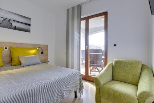 a bedroom with a bed and a chair and a window at Apartment Falu in Štinjan