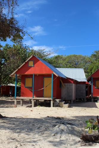 a red building with a metal roof on a beach at Sunrise Paradise/Carlito´s Place in Corn Island