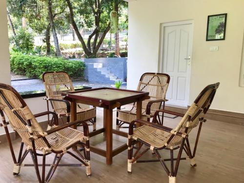 una mesa de madera con 4 sillas y una mesa con ping en Davis Farm House, en Maraiyūr