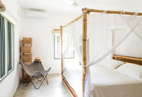 a bedroom with a four poster bed and a chair at The Cottage Bentota in Bentota