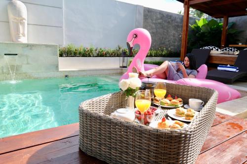 un tavolo con un fenicottero rosa accanto a una piscina di Villa Arusha Jogja a Sleman