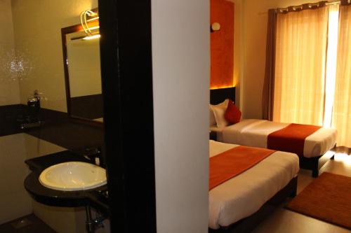 a bedroom with two beds and a sink and a mirror at Tuki Resort Pokhara in Pokhara