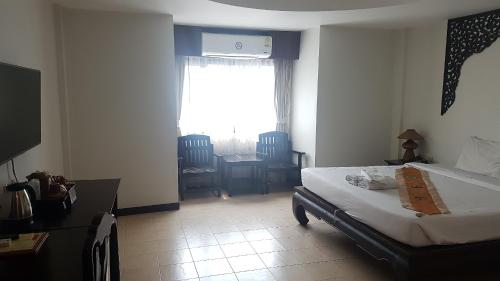 a bedroom with a bed and a table and a window at Wangburapa Grand Hotel in Chiang Mai
