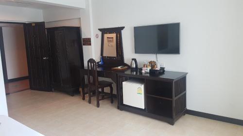 a room with a desk with a television on a wall at Wangburapa Grand Hotel in Chiang Mai