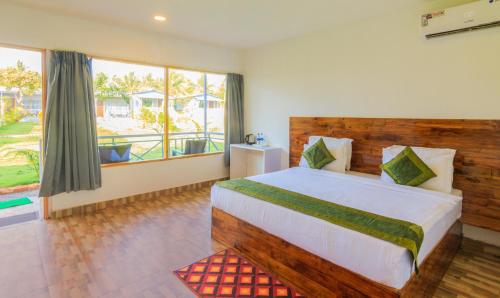 een slaapkamer met een groot bed en een groot raam bij Treebo Trend Lands End Beach Resort Morjim in Morjim