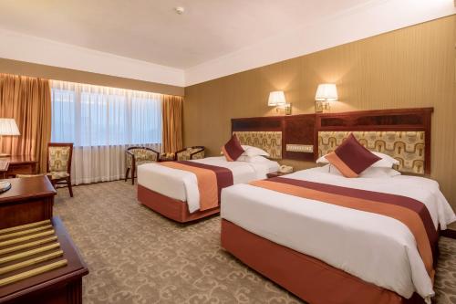 a hotel room with two beds and a desk at Asia International Hotel Guangdong in Guangzhou