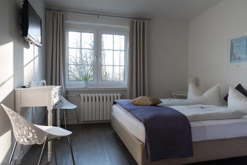 a bedroom with a bed and a desk and windows at Haus ÜberLand in Sundhagen-Niederhof