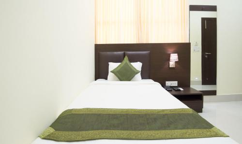 a bedroom with a large white bed with a wooden headboard at Treebo King'S Court Chandrasekharpur in Bhubaneshwar