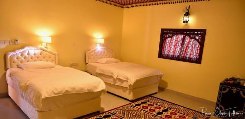 a bedroom with two beds and a window at Arabian Oryx Camp in Shāhiq