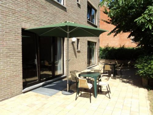 a patio with a table and chairs and a green umbrella at Budget Flats Brussels in Brussels