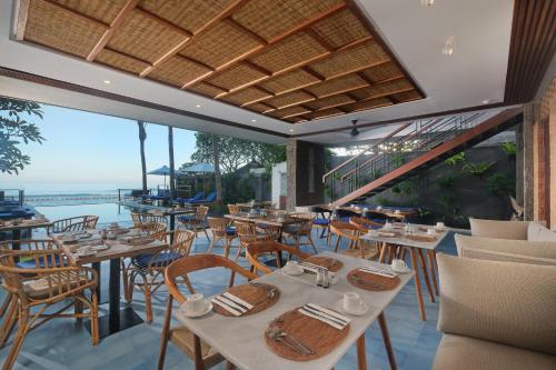 a restaurant with tables and chairs and a view of the ocean at Sagara Candidasa by AHM in Candidasa