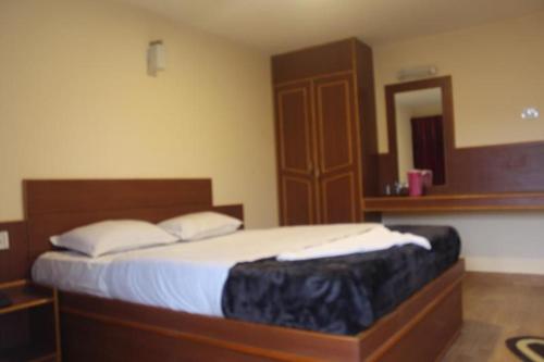 1 dormitorio con 1 cama con cabecero de madera y espejo en Nook Residency, en Ooty