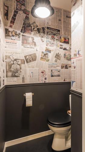 a bathroom with a toilet and newspapers on the wall at Gite "le millésime" in Épernay