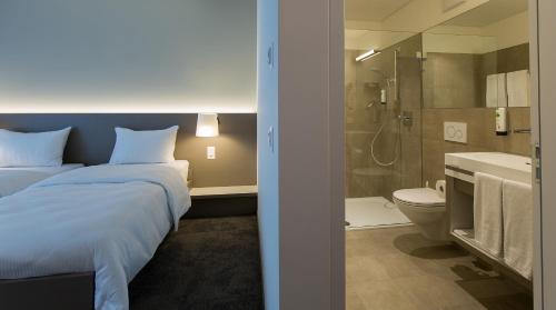 a bedroom with a bed and a bathroom with a shower at b_smart motel Landquart in Landquart