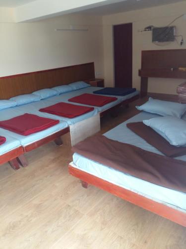 a group of three beds in a room at Nook Residency in Ooty