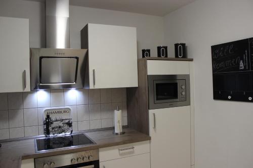 a kitchen with white cabinets and a stove and a microwave at Ferienhaus an der Grenze zu Hamburg Zentrale Lage in Neu Wulmstorf