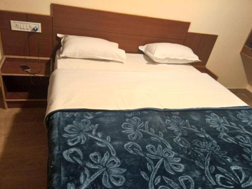1 cama grande con edredón blanco y negro en Nook Residency, en Ooty