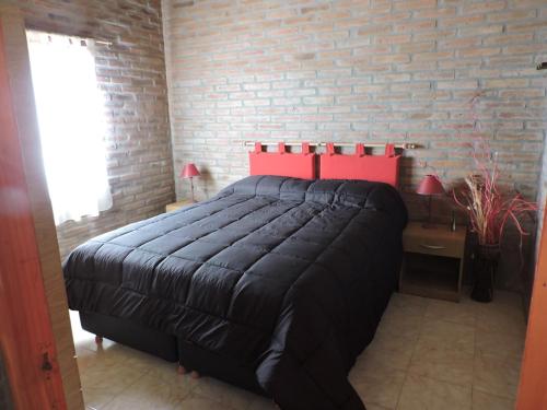 ein Schlafzimmer mit einem Bett und einer Ziegelwand in der Unterkunft CABAÑAS LOS COCKERS in Villa General Belgrano
