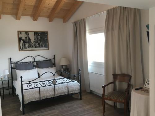 ein Schlafzimmer mit einem Bett, einem Stuhl und einem Fenster in der Unterkunft Cà Petra in Sacile