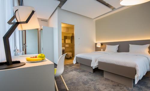 een slaapkamer met een bed en een bureau met fruit op een tafel bij b_smart motel Landquart in Landquart