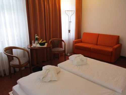 a hotel room with two beds and a couch at Vitalhotel Weisse Elster in Bad Elster