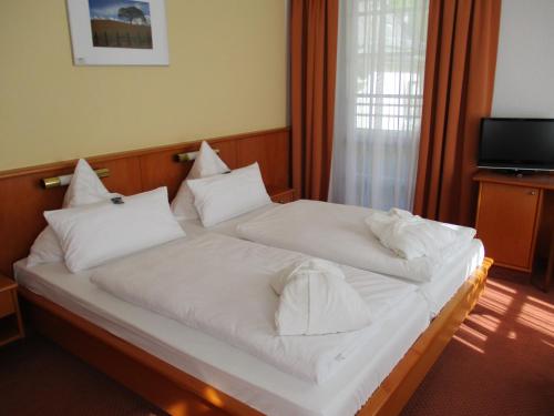 a bedroom with two beds with white sheets and pillows at Vitalhotel Weisse Elster in Bad Elster