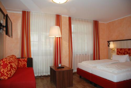 メーアスブルクにあるGästehaus Armeemuseumのベッドと赤いソファが備わるホテルルームです。
