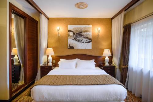 a bedroom with a bed and two lamps and a window at Mimosa Court Apartments in Nairobi