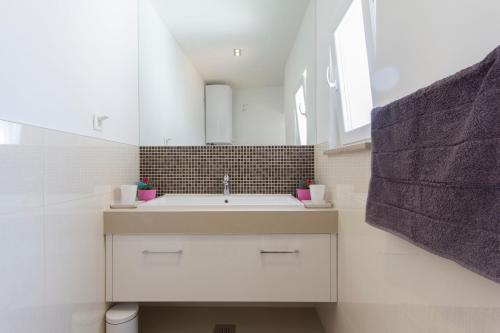 a white bathroom with a sink and a mirror at Appartment in center with parking in Pula