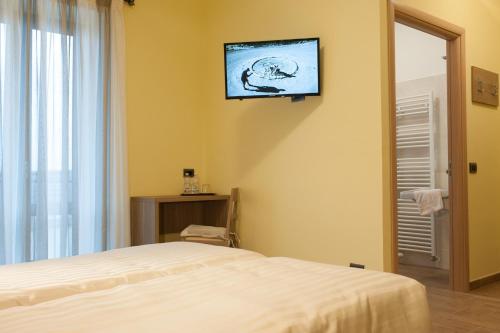 una camera da letto con un letto e una televisione a parete di Hotel Ristorante Piccadilly a Santhià