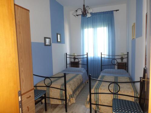 Dos camas en una habitación con paredes azules y una ventana. en Casa dei Pini, en Cortona