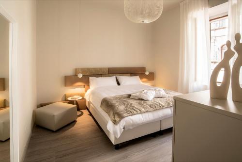 a white bedroom with a bed and a table at Cinquanta4 Charme Apartment in Trento