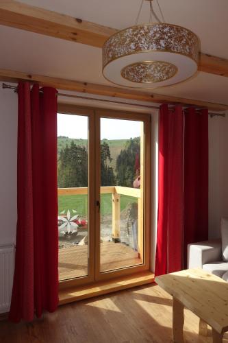 a living room with a large window with red curtains at Willa Zaolzie in Istebna