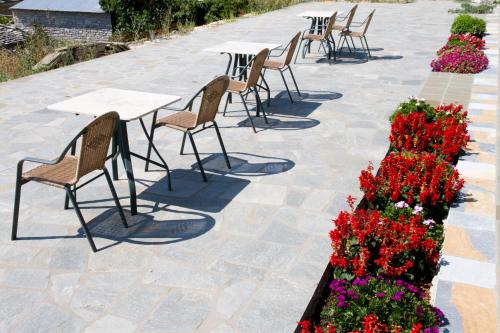 a row of tables and chairs with red flowers at Hotel Monodendri in Monodendri
