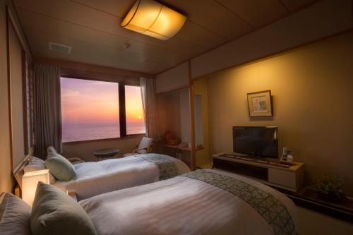 a hotel room with two beds and a flat screen tv at Jukaitei in Kyotango
