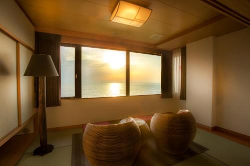 a room with two chairs and a window with the ocean at Jukaitei in Kyotango