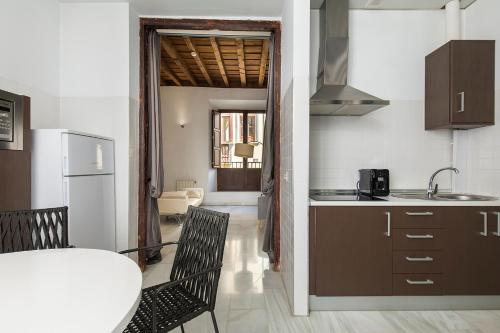 a kitchen with a table and chairs and a kitchen with a refrigerator at Elvira Suites in Granada