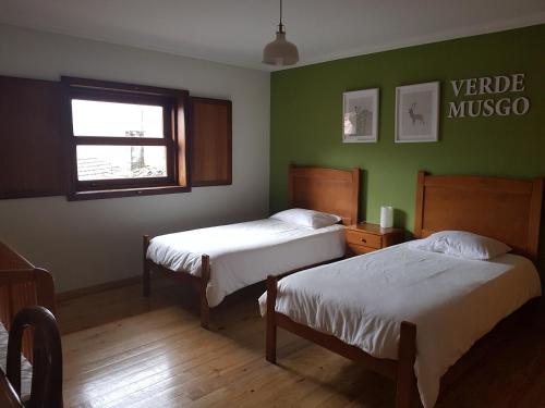 two beds in a room with green walls at Abrigo da Geira House in Campo do Gerês