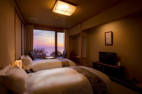 a hotel room with two beds and a television at Jukaitei in Kyotango