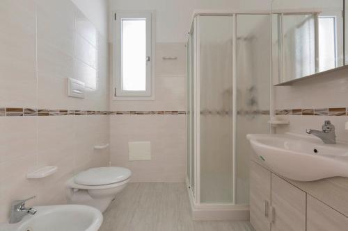 Baño blanco con aseo y lavamanos en Residence Pianeta Mare, en Torre Lapillo
