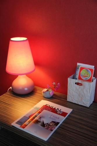 a table with a lamp and a magazine on it at Hôtel Restaurant le Panorama in Évian-les-Bains