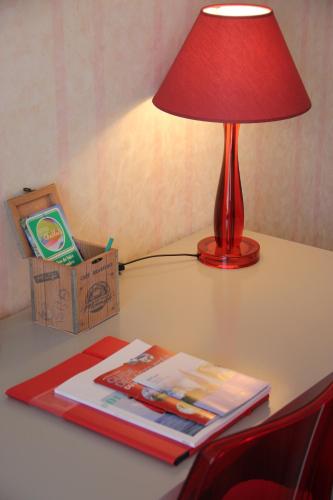 a red lamp sitting on a table next to a book at Hôtel Restaurant le Panorama in Évian-les-Bains