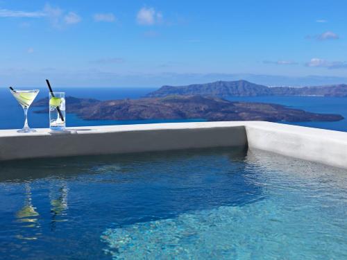 a swimming pool with two glasses on the edge of it at Lilium Hotel Santorini in Fira
