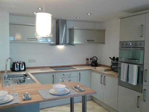 a kitchen with white cabinets and a table with dishes on it at Warwick Market Place Apartment in Warwick