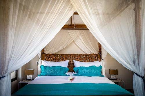 1 dormitorio con 1 cama con cortinas blancas y almohadas azules en Casa Baliza, adults only, en Alhaurín el Grande