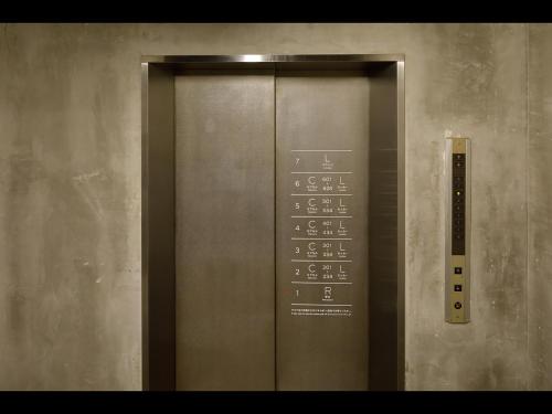 an elevator with a metal door with numbers on it at Do-C Gotanda in Tokyo